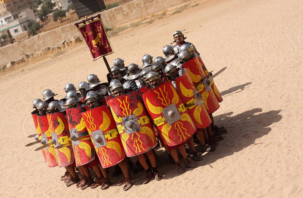 Roman Army reenactors holding shields in a protective formation. 